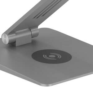 Close-up of a modern desk lamp base featuring a circular wireless charging pad on the surface.